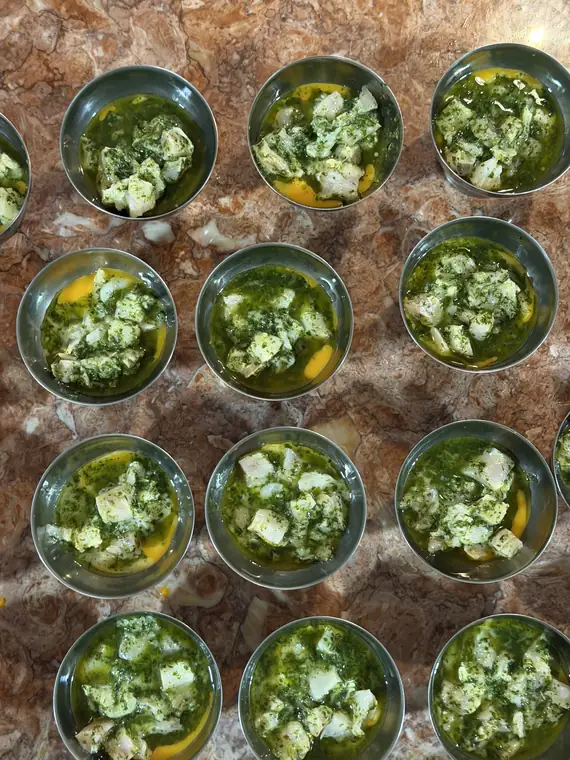 Copos com creme verde de ervas e queijo fresco, preparados em fila.