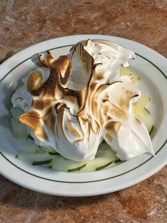 Sobremesa de merengue tostado numa travessa oval.