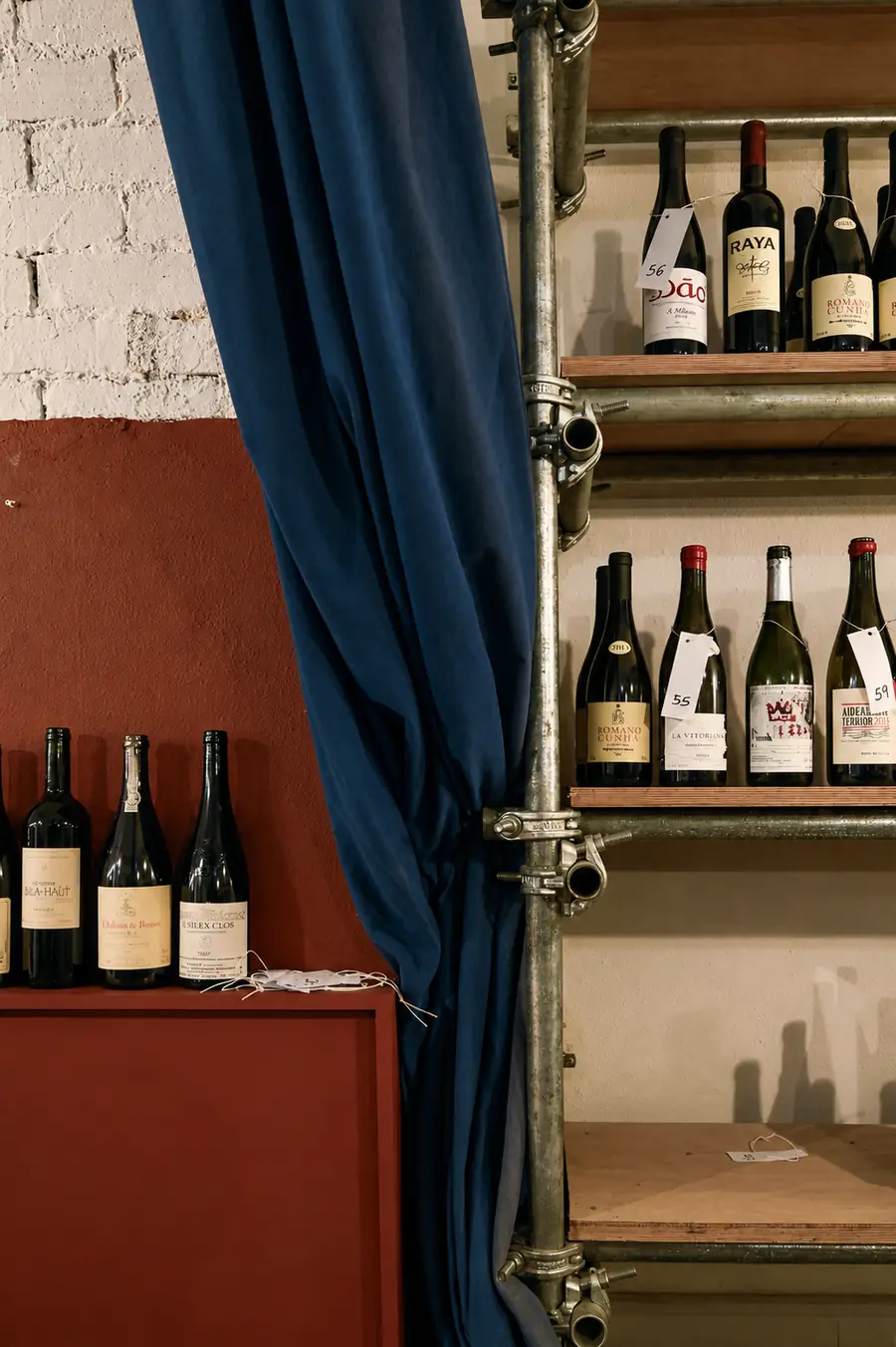 Garrafas de vinho sobre um móvel, junto à cortina azul.