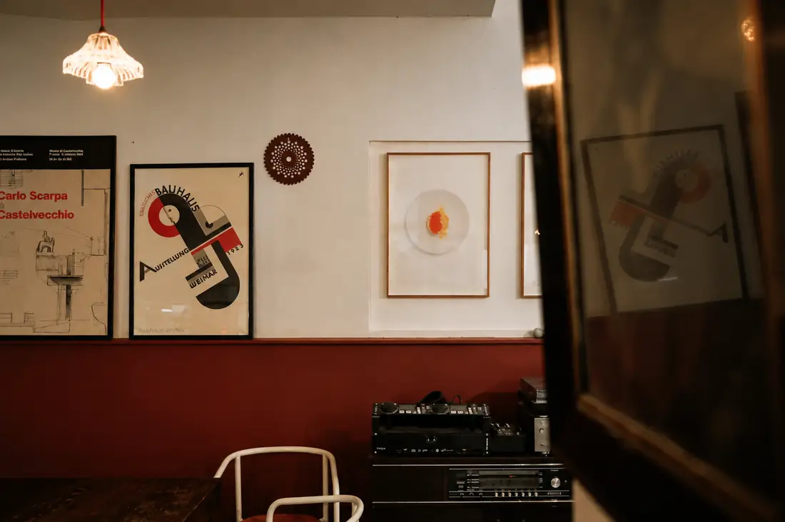 Gira-discos e amplificador sobre um móvel antigo, com cartazes na parede.