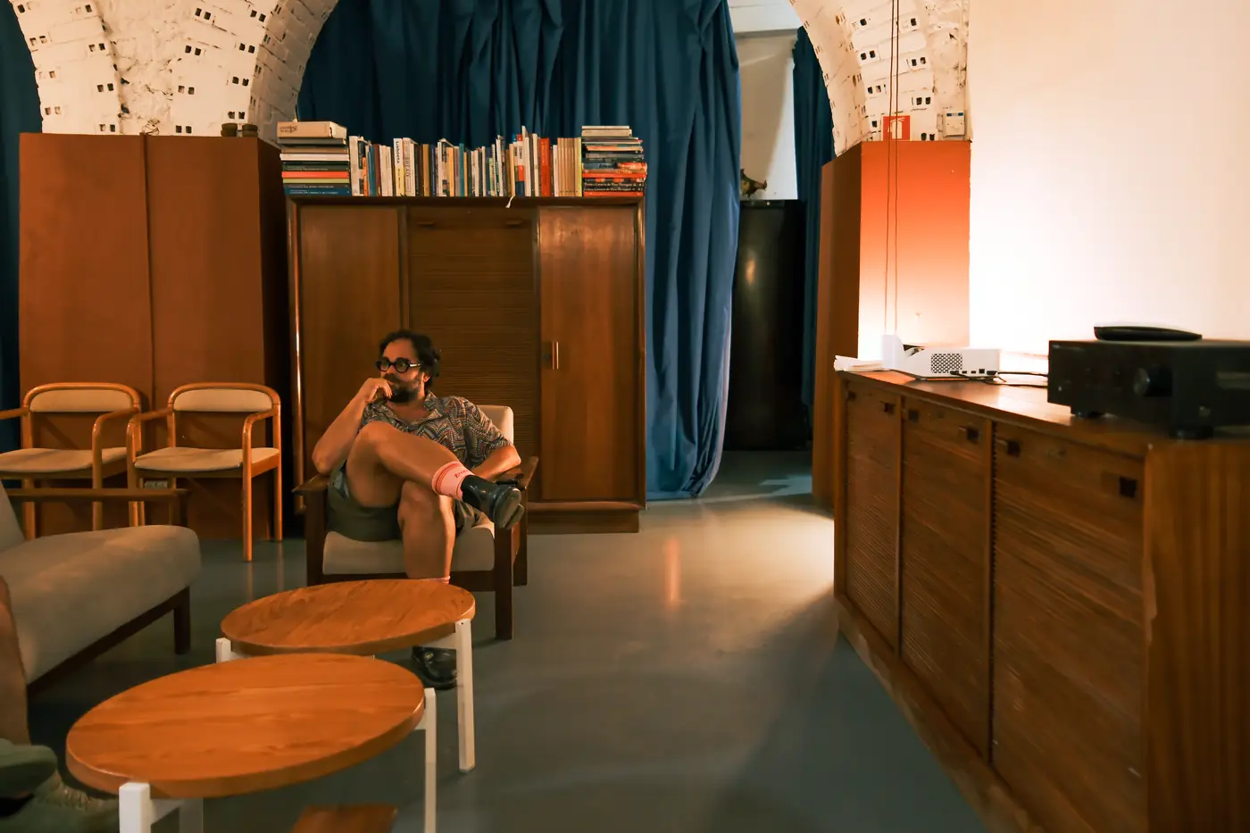 Zona de estar com cadeirões, mesa baixa e estante de livros.