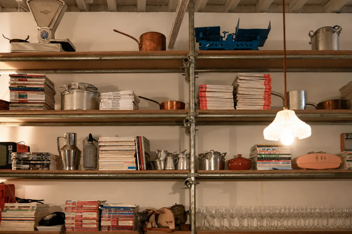 Prateleira da cozinha com tachos, livros de cozinha e loiça.